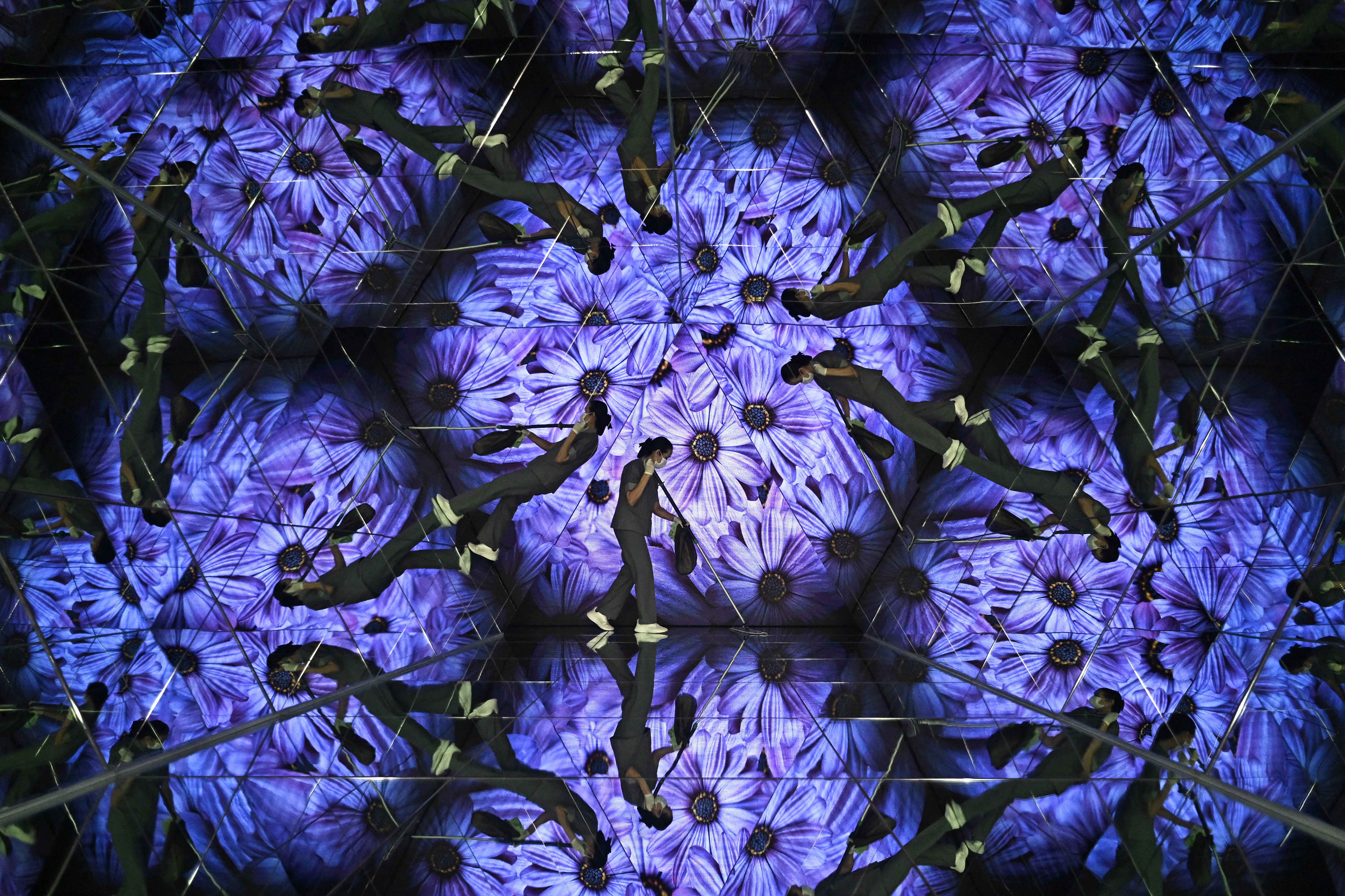 Workers use brooms to clean the mirrors, which are reflected in multiple mirrors.