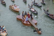 A string quartet plays while standing on a boat shaped like a giant violin in Venice.