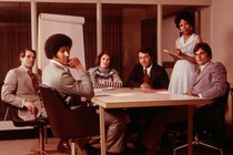 A photograph of workers gathered in a conference room