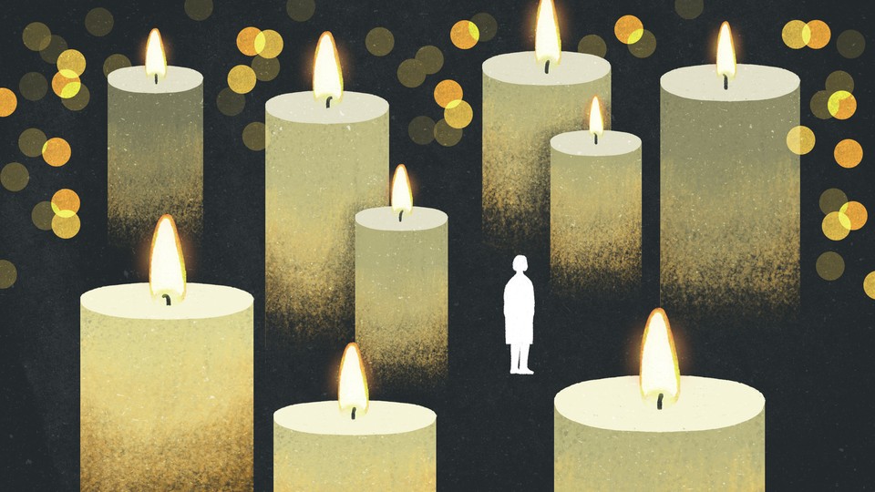 The silhouette of a woman stands small and alone among oversized lit candles