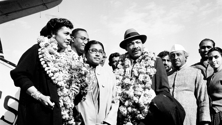 Martin Luther King, Jr. and his wife Coretta, both wearing garlands, are received by admirers after landing at the airport in New Delhi, India, in 1959.
