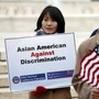 Two Asians hold signs opposing racial discrimination in college admissions outside the Supreme Court