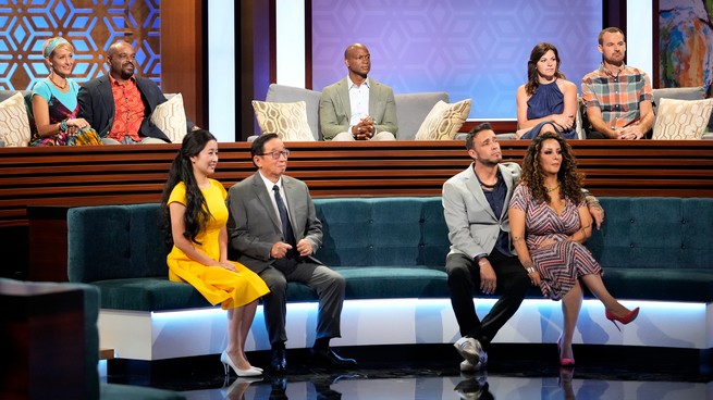 Four couples and one single man sit on couches in an amphitheater.