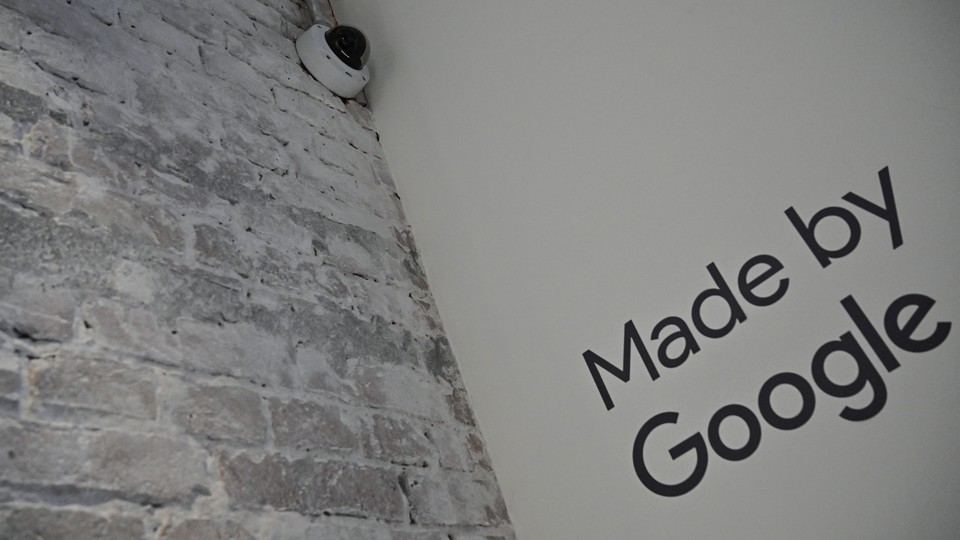 A security camera on a white brick wall next to a sign that says "Made by Google"