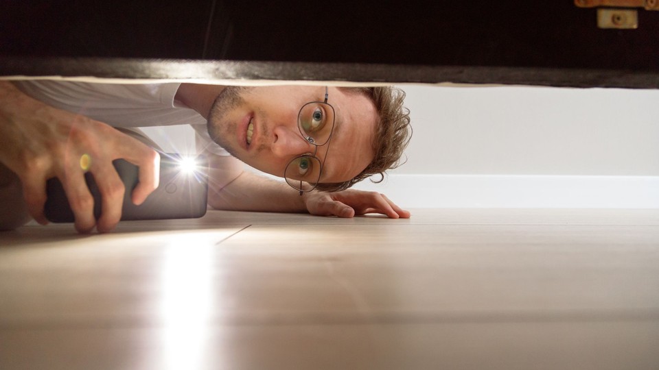 Man looking under his bed with a flashlight