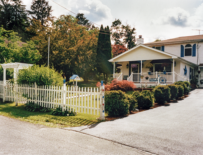 photo of house with trees, porch, and white picket fence