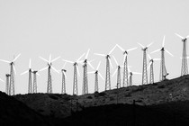 A black-and-white photo of wind turbines along a hillside