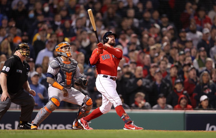 A professional baseball player looks up after a big hit, as the catcher, the umpire, and a stadium full of fans watch the rising ball.