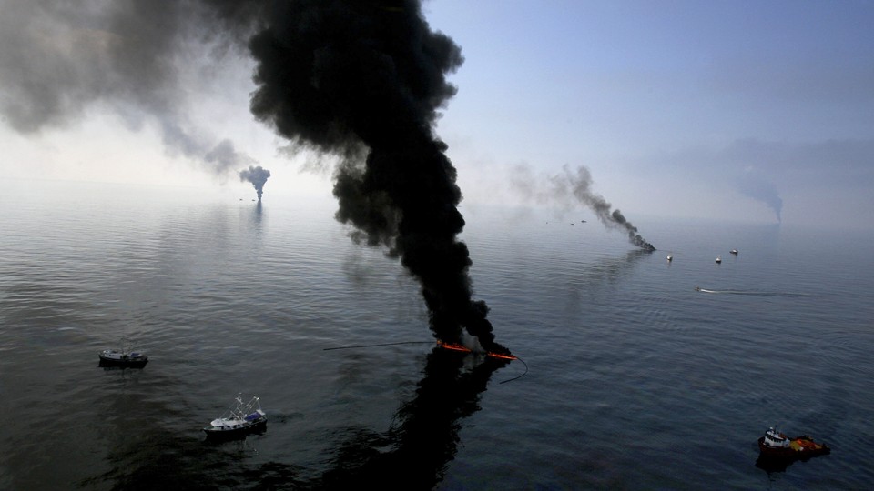 Black smoke billows from multiple points on an ocean expanse.