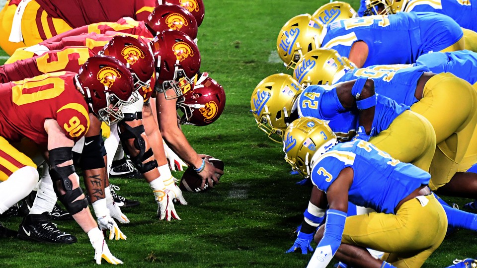 Two football teams squat, facing each other.