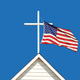 photo-illustration of white cross atop white wooden church steeple with U.S. flag flying from it against blue sky