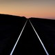 A pair of railroad tracks extend into the sunset