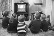 A black-and-white photo of children watching television