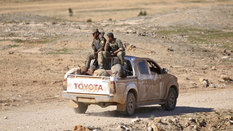 Syrian Democratic Forces fighters ride a pickup truck with Islamic State fighters held as prisoners.