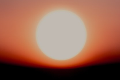 Color picture of a fuzzy white orb against an orange, red, and black background
