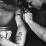 a black-and-white photo of someone getting their upper arm tattooed