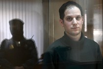 U.S. journalist Evan Gershkovich looks out from inside a defendants' cage before a hearing