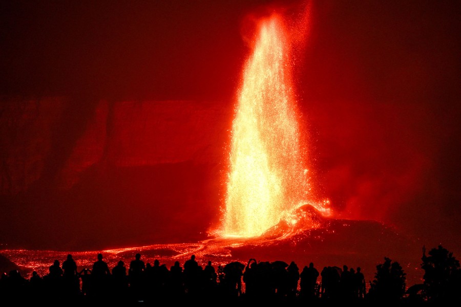 Lava erupts from a crater in Hawaii, as onlookers watch.