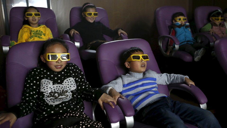 Children sit in purple movie-theater chairs, wearing disposable 3-D glasses.