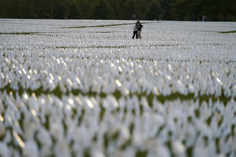 A couple looks at the white flags that are part of the installation.