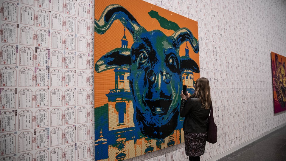 A person takes a photo of a Lego portrait of a bull.