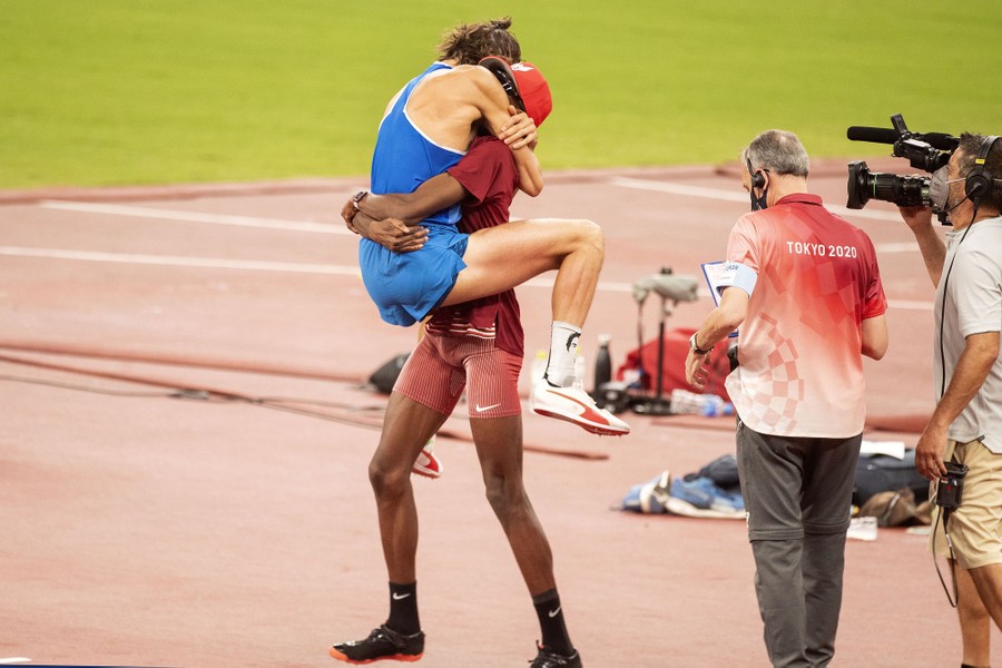 Two Olympic athletes embrace in celebration.