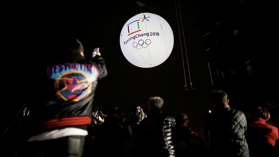 Photographers take photographs of a giant inflatable ball bearing the logo of the 2018 Pyeongchang Winter Olympics.