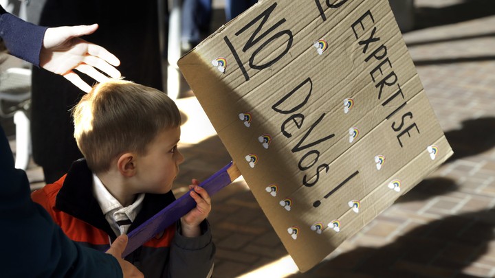 A 3-year-old boy carries a sign opposing Betsy DeVos`