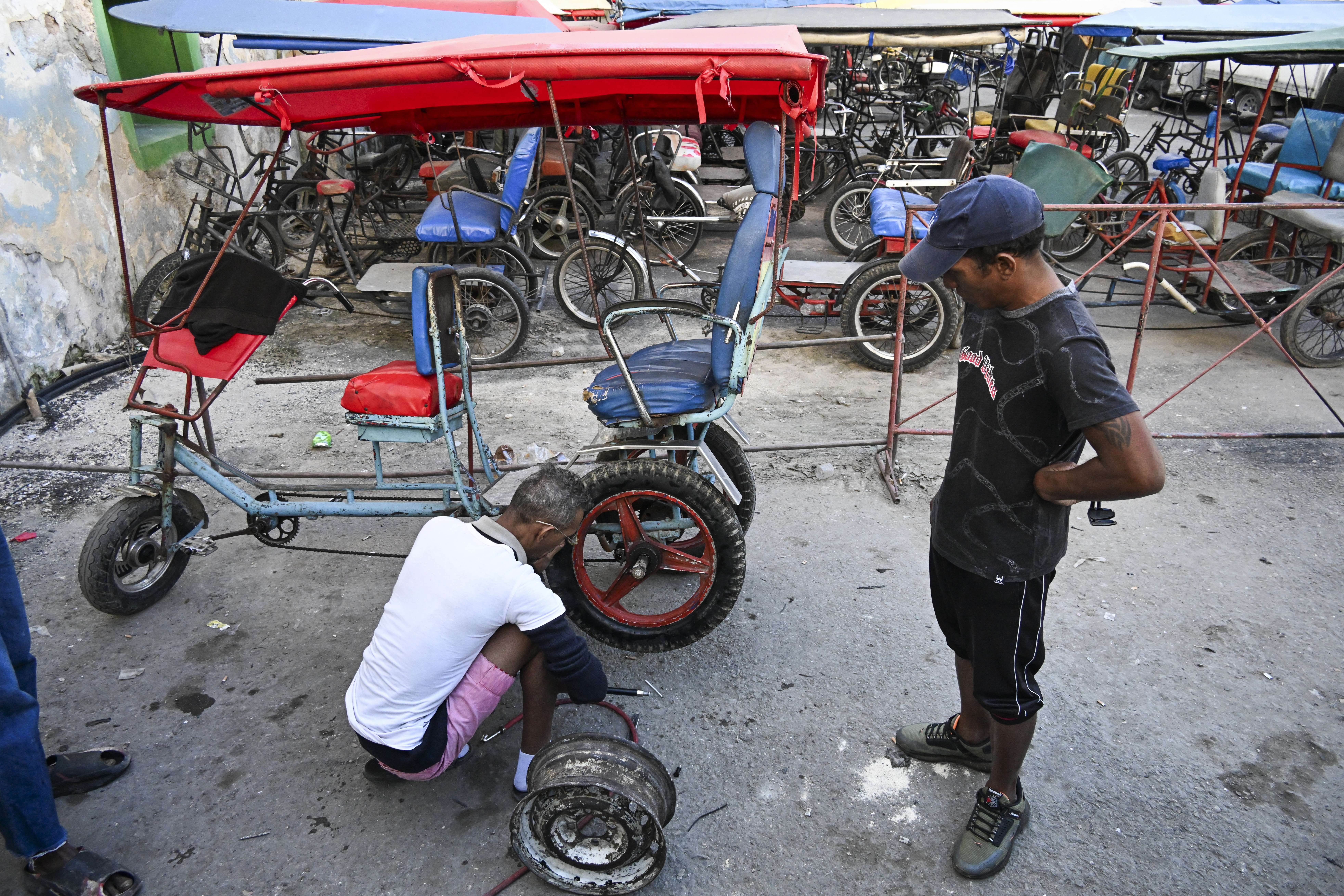 A mechanic repairs a flat tire on a cycle rickshaw.
