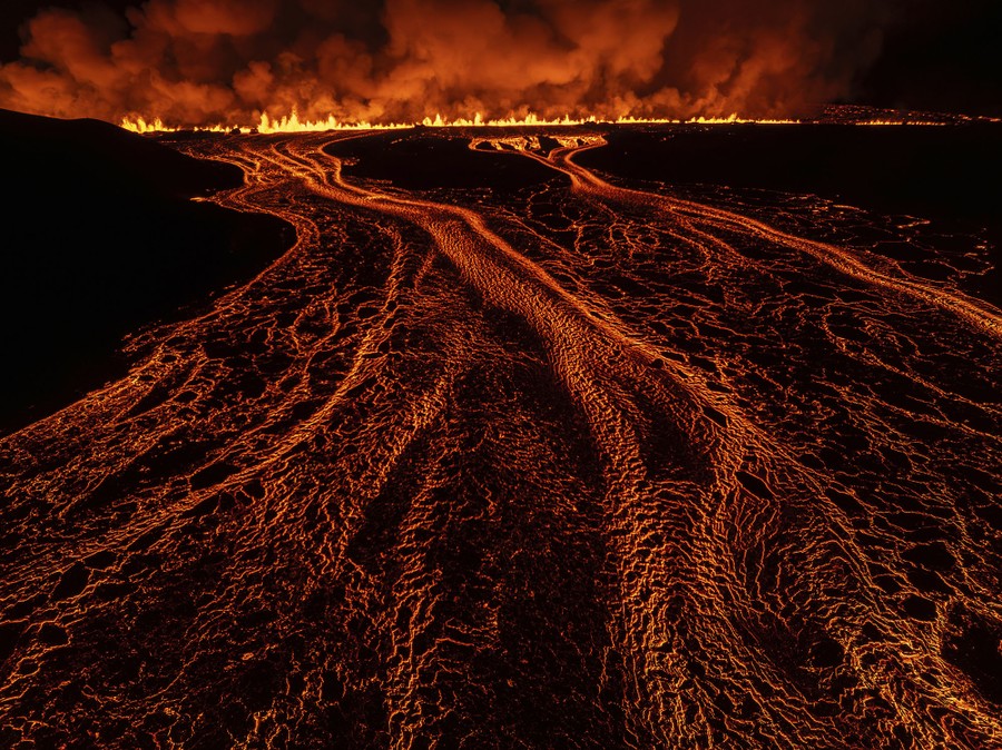 Lava flows from an open volcanic fissure at night.