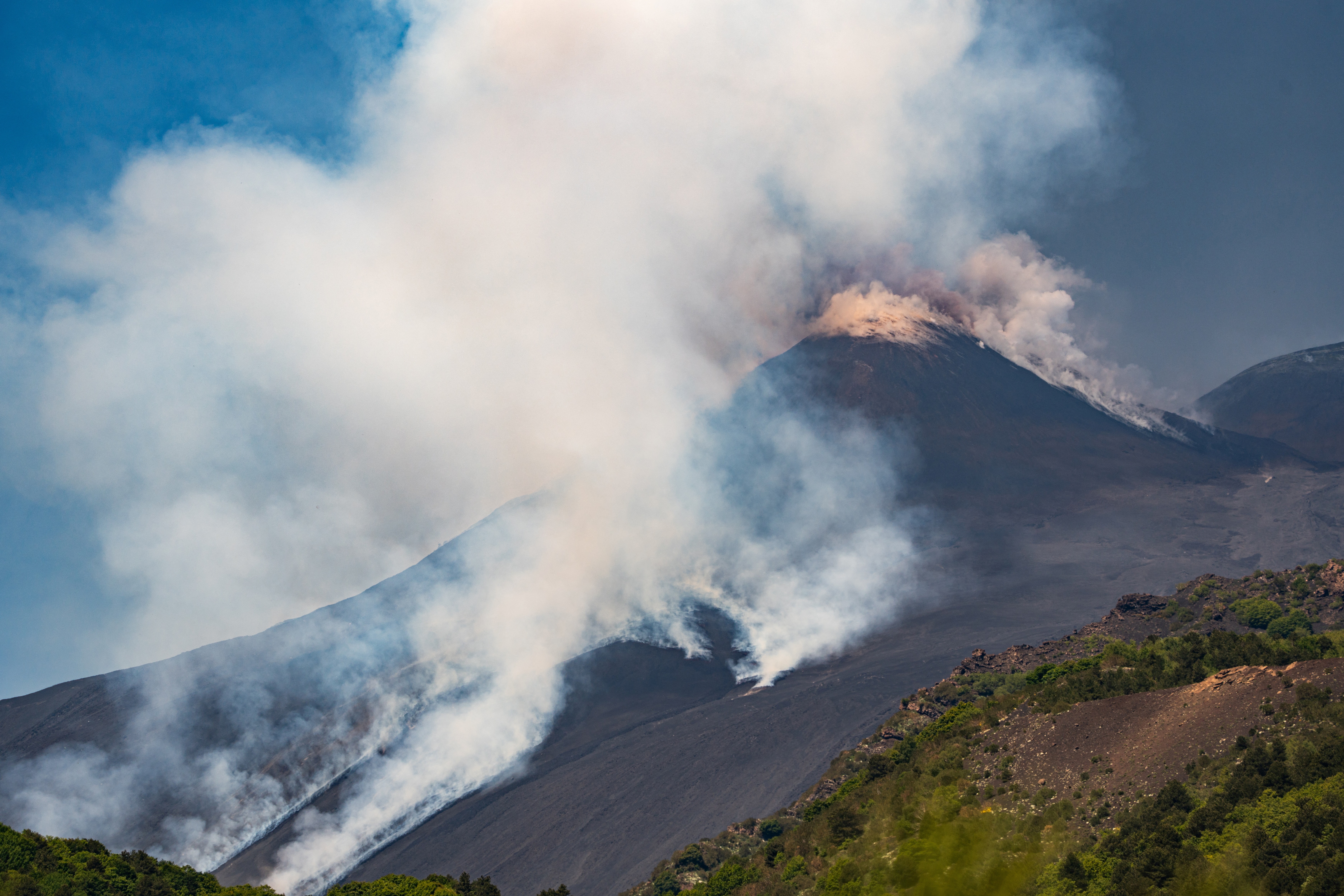 Steam rises from the top and flanks of a volcano.