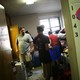 A family unpacks a student's luggage and furniture in a dorm room. 