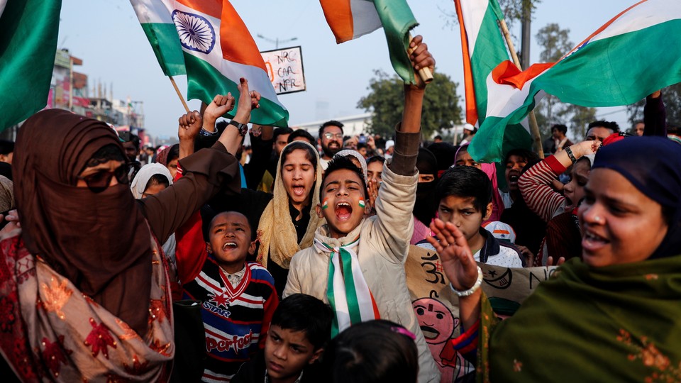 People hold signs and India's national flag during a protest in New Delhi, India.
