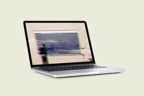 An open laptop showing the reflection of a teacher in a classroom