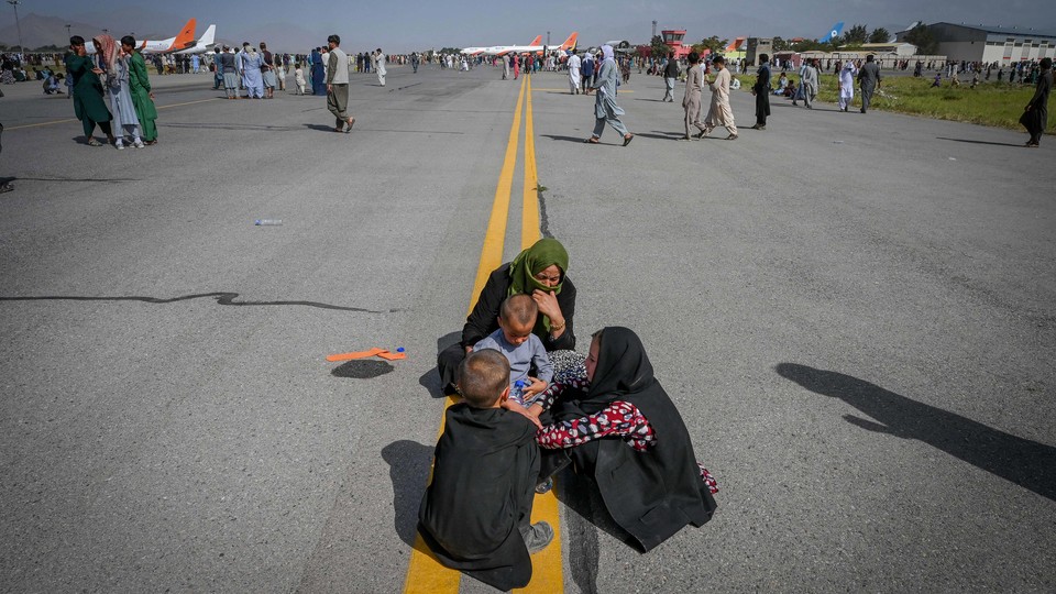 Afghan people waiting on the tarmac at the Kabul airport.