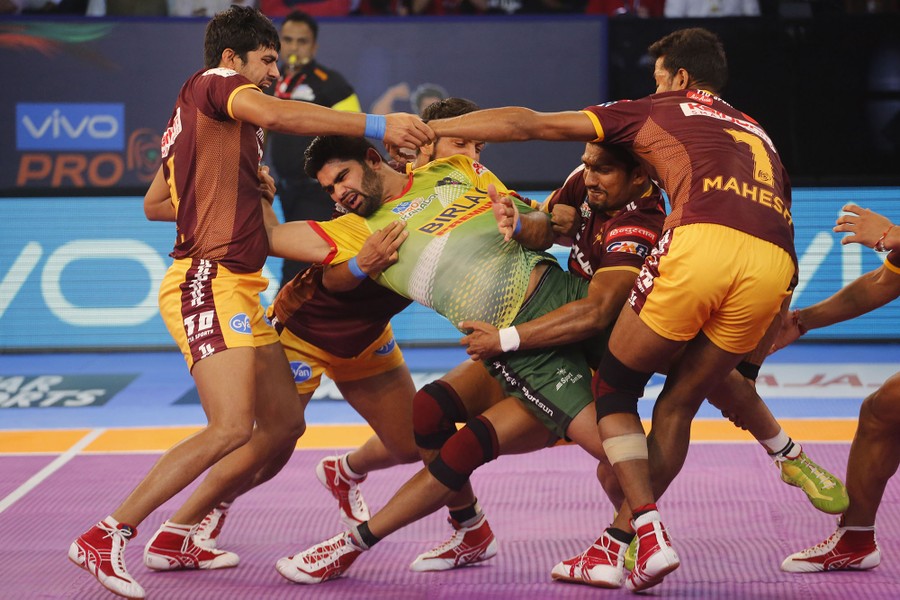 U.P. Yoddha's players pin down Patna Pirates Captain Pardeep Narwal, in green jersey