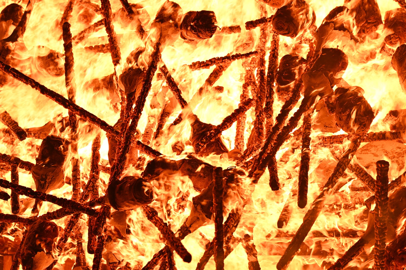A close view of dozens of burning torches that have been tossed into a pile.