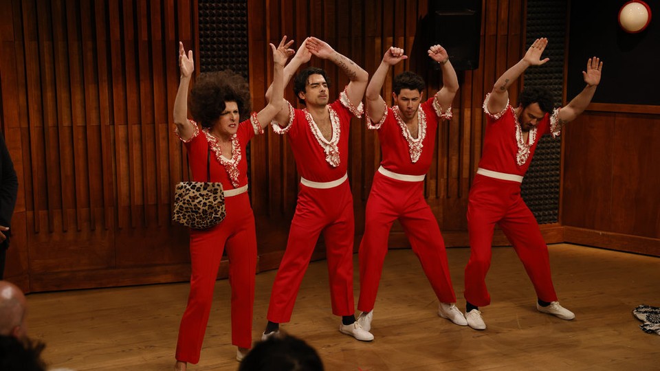 Molly Shannon and the three Jonas Brothers in matching red pantsuits