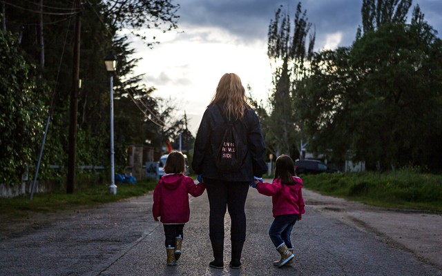 A mom with two children holding her hands.