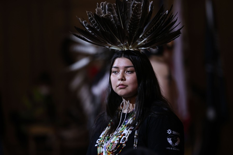 A person wears a feathered headdress during a celebration.