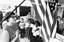 An archival photo of an American classroom saluting the American flag