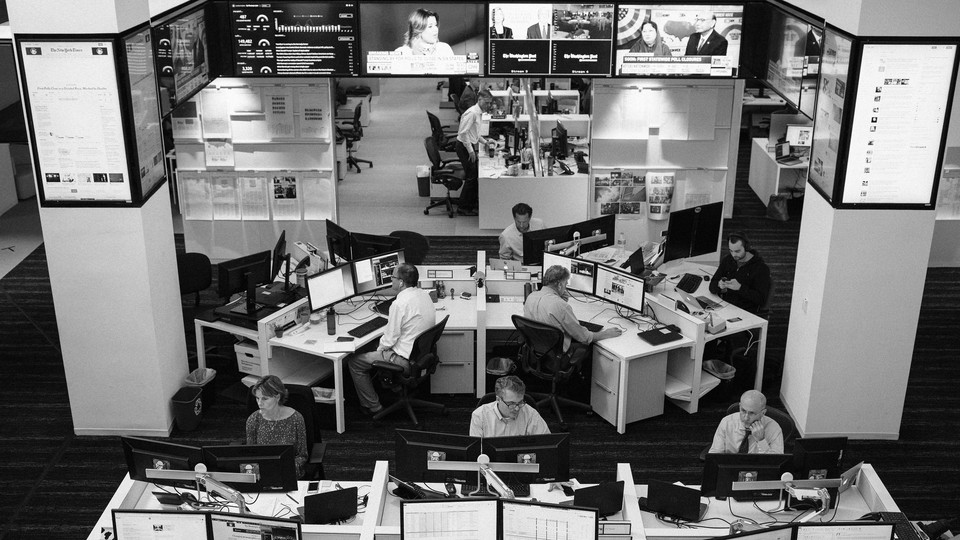 A black-and-white photograph of employees working in the Washington Post newsroom