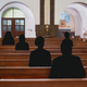 Church pews with black silhouettes of congregants