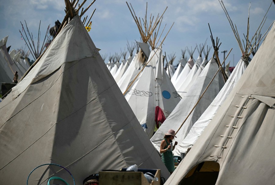 People walk among several rows of tepees.