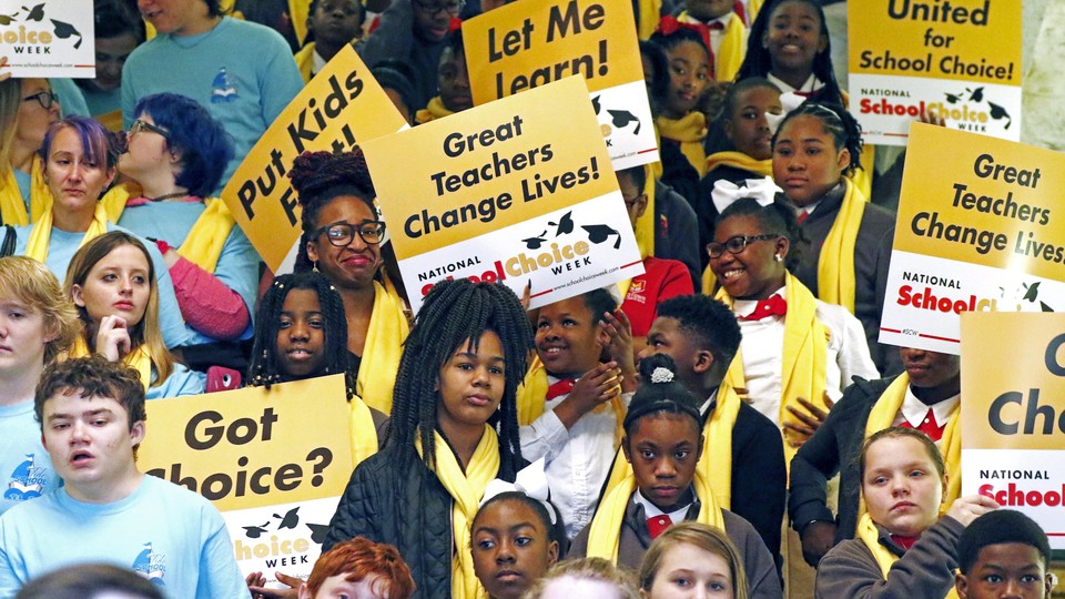 People hold signs reading "Let me learn," "United for school choice," and "Great teachers change lives."