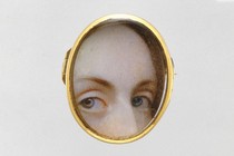 Part of a woman's face looking captured in a locket