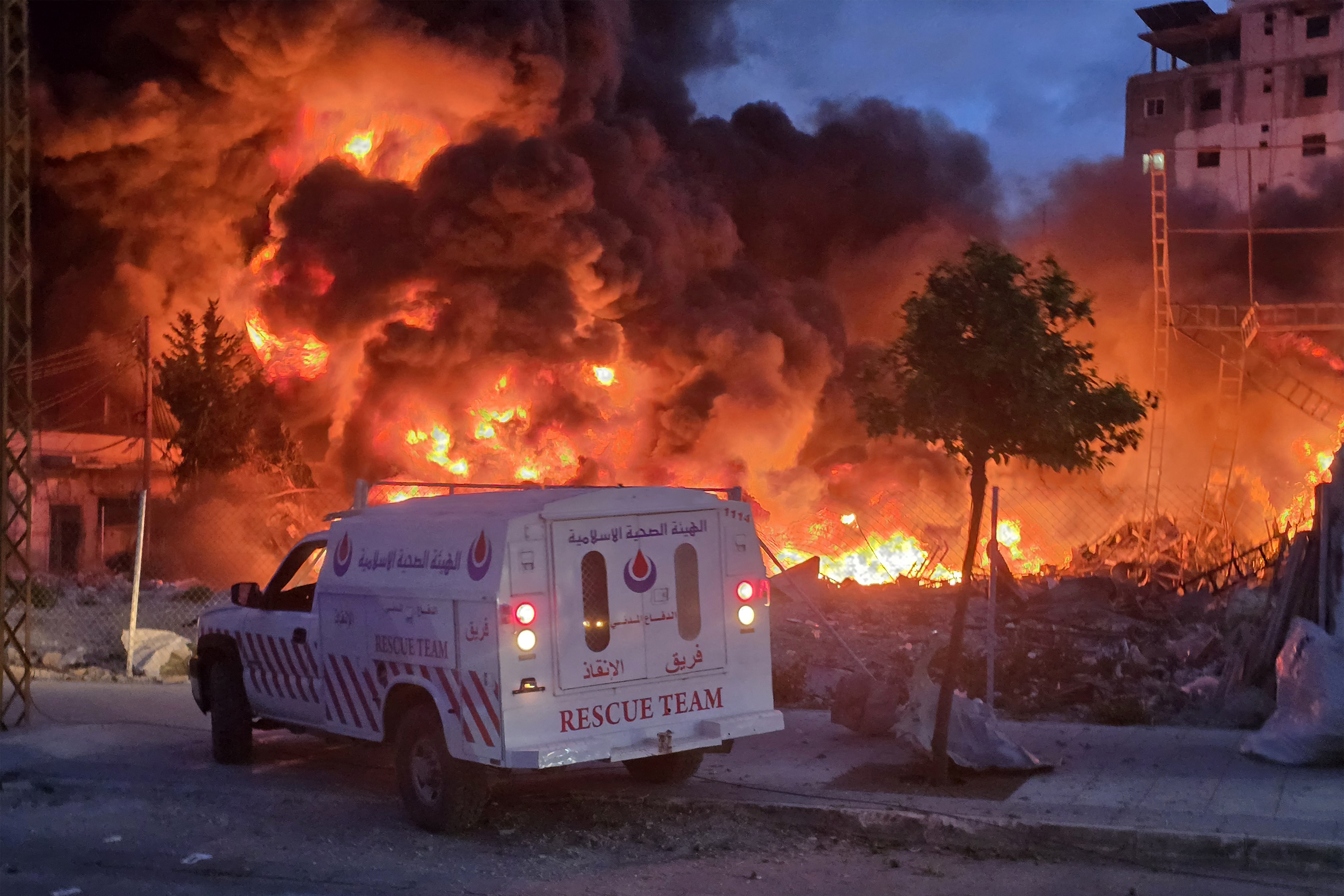 An ambulance is parked near a fire after an aerial attack.