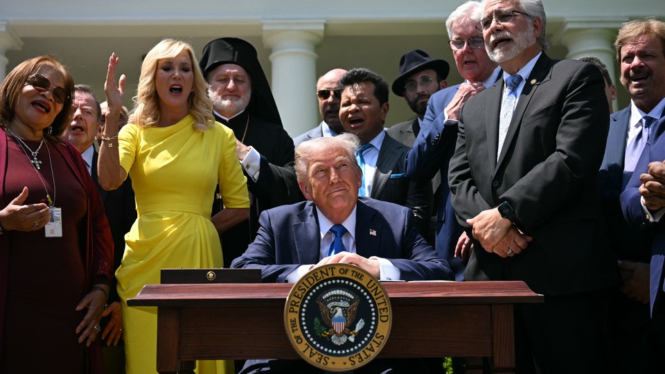 Trump sits at a desk surrounded by faith leaders
