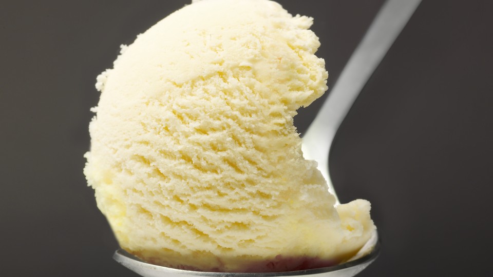 A scoop of vanilla ice cream rests on a spoon.