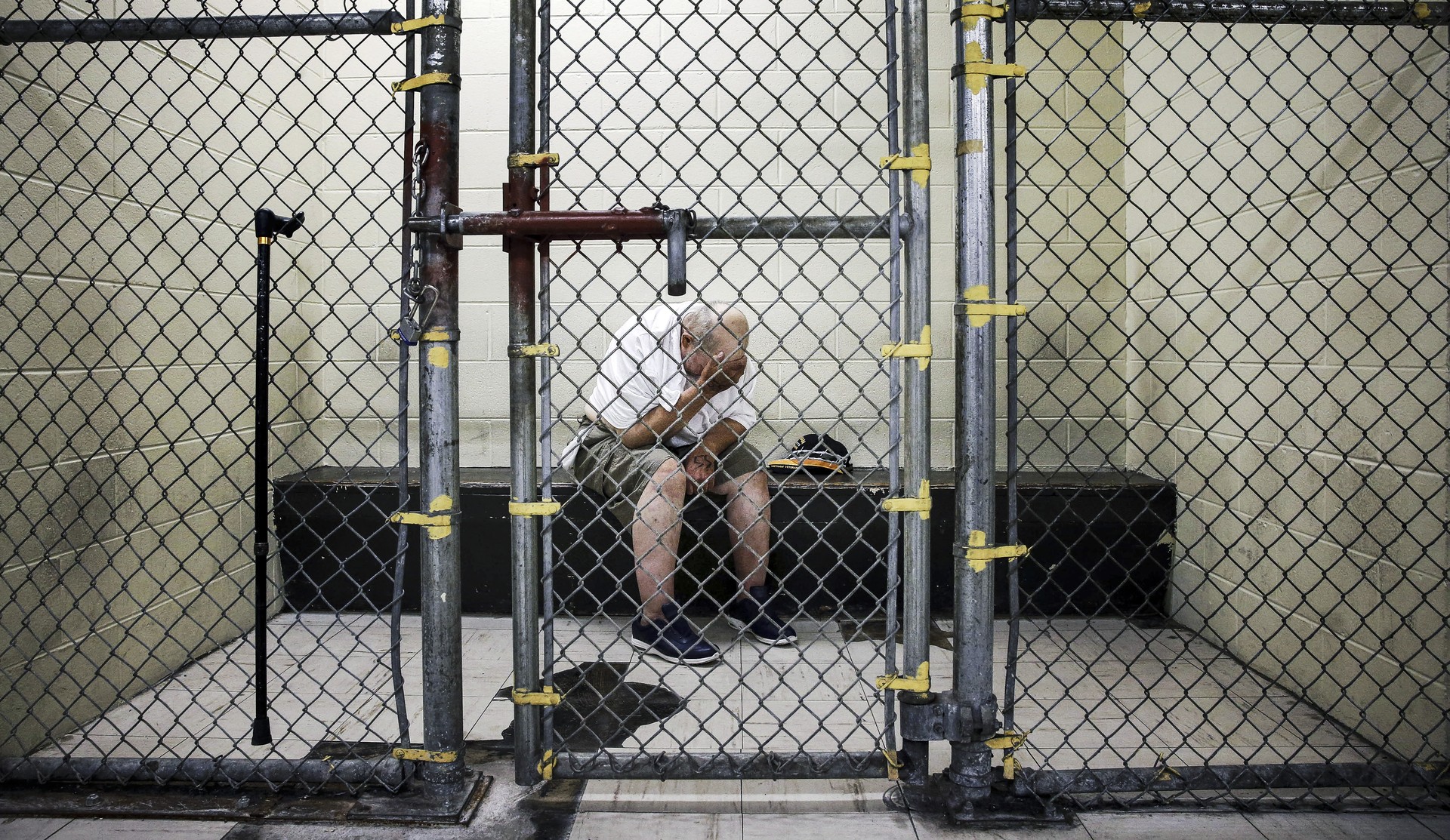 A man in a jail cell with his head in his hands